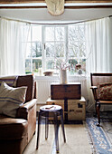 Vintage suitcases with chair and sofa in window of Warwickshire farmhouse, England, UK