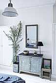Large olive tree with antique cabinet in bedroom of Edwardian London flat, UK