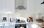 Extractor above gas hob with teapot in kitchen of Edwardian London flat, UK