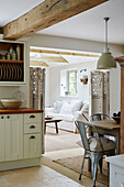 Beamed open plan kitchen with table and chairs in Grade II listed West Sussex barn conversion, UK