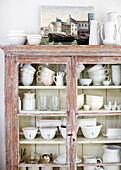 Collection of crockery in glass fronted cabinet West Sussex barn conversion, UK