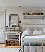 Vintage mirror and drawers at bedside in West Sussex barn conversion, UK