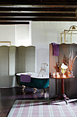 Faltwand und Rolltop-Badewanne mit Tartan-Teppich im Badezimmer eines schottischen Schlosses, UK