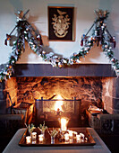 Beleuchtete Kerzen und Feuer mit Weihnachtsgirlande in einem schottischen Schloss, UK