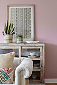 Framed textile on glass fronted cabinet with sofa in pastel pink living room Tunbridge Wells home, Kent, UK