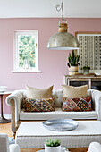 Pendant light in pastel pink living room with fabric cushions in Tunbridge Wells home, Kent, UK
