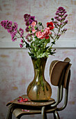 Summer flowers in glass vase on chairs in Camber cottage, East Sussex, UK