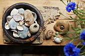 Seashells and pebbles in wooden bowl on table in Camber cottage, East Sussex, UK