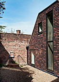 Gravel courtyard and windows of brick barn conversion, Rye, East Sussex