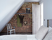 Clothes hang on exposed brick wall in bedroom of Rye barn conversion, East Sussex