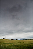 Telegraph poles in field under stormy sky Berkshire, England, UK