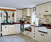 Cream oven and fitted units with butler sink in Sandford St Martin cottage, Oxfordshire, UK