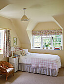 Einzelbett und Stuhl im Mädchenzimmer mit geblümten Vorhängen und Jalousien in einem Cottage in Sandford St Martin, Oxfordshire, UK