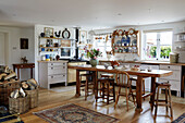 Wooden table and stools with firewood in open plan kitchen Oxfordshire farmhouse, UK
