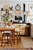 Wooden table and stools with kettle on hob in Oxfordshire farmhouse, UK