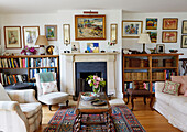 Cut flowers on coffee table with bookshelves and framed art in Oxfordshire farmhouse, UK