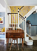 Vintage writing desk and stool in papered staircase of Deddington home, Oxfordshire, UK