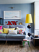 Große Retro-Lampe und Sofa mit Kunstwerken und dem Wort JOY" in einem Haus in Deddington, Oxfordshire, UK"