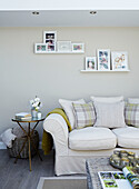 Gerahmte Fotos auf einem Regal über dem Sofa in einem Wohnzimmer in North Yorkshire, UK