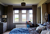 Unmade bed with view to sea from Northumbrian home, UK