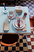 Messer und Gabel auf Formica-Tischplatte mit karierten Bodenfliesen in einem bretonischen Landhaus in Frankreich