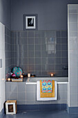 Grau gefliestes Badezimmer mit beleuchteten Teelichtern in einem bretonischen Landhaus in Frankreich