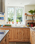 Wooden fitted kitchen with sink at window in Bath home, Wiltshire, UK
