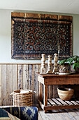 Decorative artwork above wooden table with ornaments in Devon home, UK