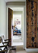 Vintage chairs and view through wood clad hallway to bedroom in Devon home, UK