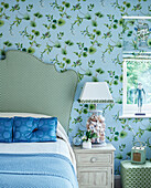 Green and blue bedroom in contrasting patterns with seashell filled lamp base Cotswolds cottage, UK