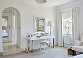 Dressing table and mirror at window in bedroom with arched doorway inYork home, UK