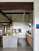 Kitchen island and bookcases with concrete flooring and structural beams in Sligo home, Ireland