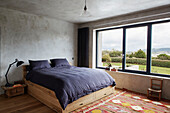 Doppelbett auf Holzgestell mit schwarzer Bettdecke und Blick auf die Landschaft von Sligo, Irland
