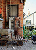 Old metal wheelbarrow and brazier with architectural salvage in Devon, UK