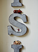 Toy pigs and soldiers with wall mounted letter 'S' in Devon home, UK