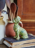 Glazed dog statue on album with wooden spoons in Devon home, UK