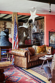 Large animal heads and US flag with brown Chesterfield in Devon home, UK