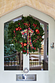 Christmas wreath on glass paned front door of Cotswolds home, UK