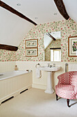 Badezimmer mit Blumentapete und gepolstertem antiken Stuhl in Cotswolds home, UK