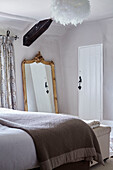 Beige blanket and gilt framed mirror in Devon bedroom, UK