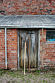 Gardening tools on brick shed at Old Lands kitchen garden Monmouthshire, UK