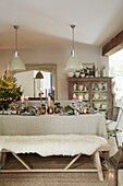 Cream pendant lights above dining table set for Christmas in West Sussex home, UK
