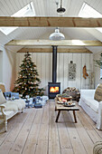Lit woodburner and Christmas tree in Gustavian living room of West Sussex home, UK