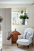 White armchair at window with open door in West Sussex home, UK