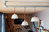 Three small pendant lights wired to scaffold pole in converted shipping container Bedford, UK