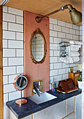 Gilt framed mirror above basin with salvaged light in converted shipping container Bedford, UK