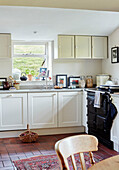 Black AAG and white fitted units in renovated Yorkshire farmhouse kitchen, UK