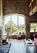 Chair in window with double height exposed stone mezzanine in renovated Yorkshire farmhouse, UK