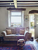 Two seater sofa under window in renovated Yorkshire farmhouse, UK