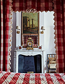 Antique clock on fireplace with gingham fabric and four postered bed Foix, Ariege, France